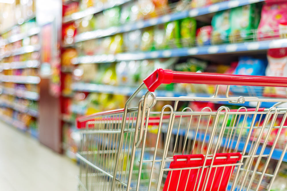 Supermarket interior, empty red shopping cart.