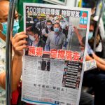 TOPSHOT - A commuter reads a copy of the Apple Daily newspaper on a train in Hong Kong on August 11, 2020, a day after authorities conducted a search of the newspaper's headquarters after the companys founder Jimmy Lai was arrested under the new national security law. - Hong Kong pro-democracy media tycoon Jimmy Lai was arrested on August 10 and led in handcuffs through his newspaper office as police raided the building, part of a sweeping crackdown on dissent since China imposed a security law on the city. (Photo by ISAAC LAWRENCE / AFP)