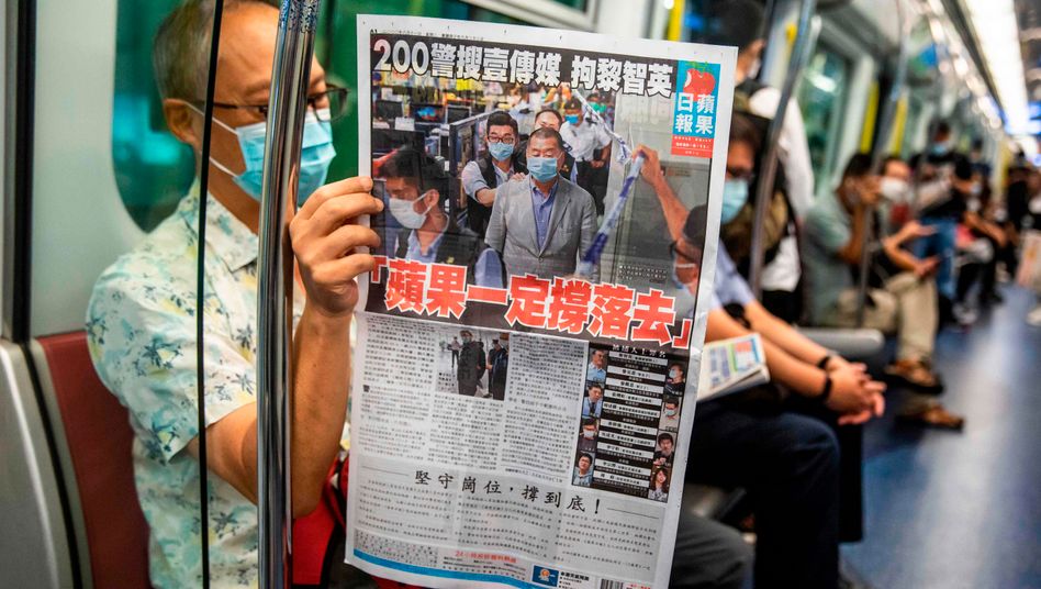 TOPSHOT - A commuter reads a copy of the Apple Daily newspaper on a train in Hong Kong on August 11, 2020, a day after authorities conducted a search of the newspaper's headquarters after the companys founder Jimmy Lai was arrested under the new national security law. - Hong Kong pro-democracy media tycoon Jimmy Lai was arrested on August 10 and led in handcuffs through his newspaper office as police raided the building, part of a sweeping crackdown on dissent since China imposed a security law on the city. (Photo by ISAAC LAWRENCE / AFP)